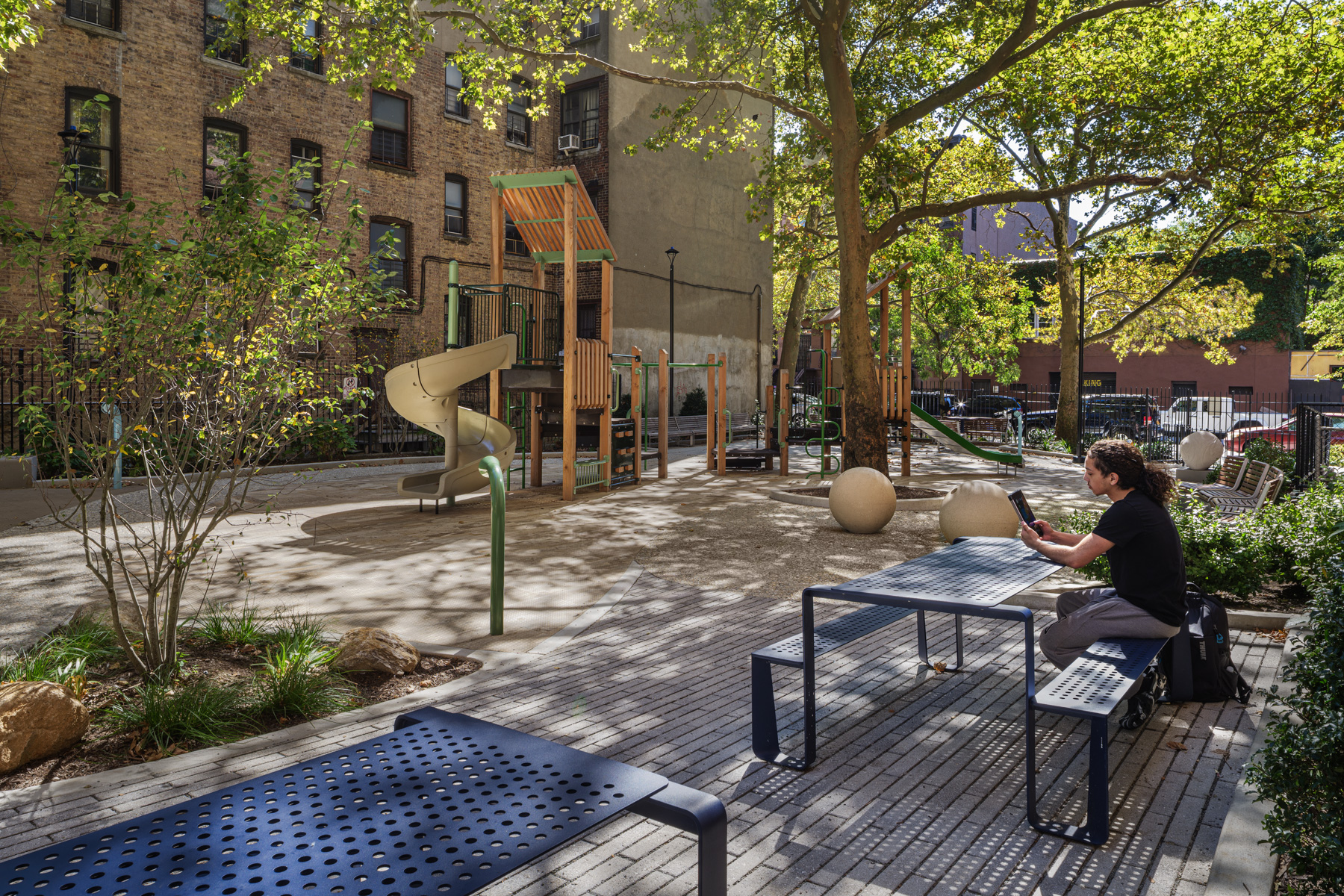 Landscape renovation at NYCHA PACT Audubon Houses showing playground, seating area, and shaded gathering space in Washington Heights Manhattan