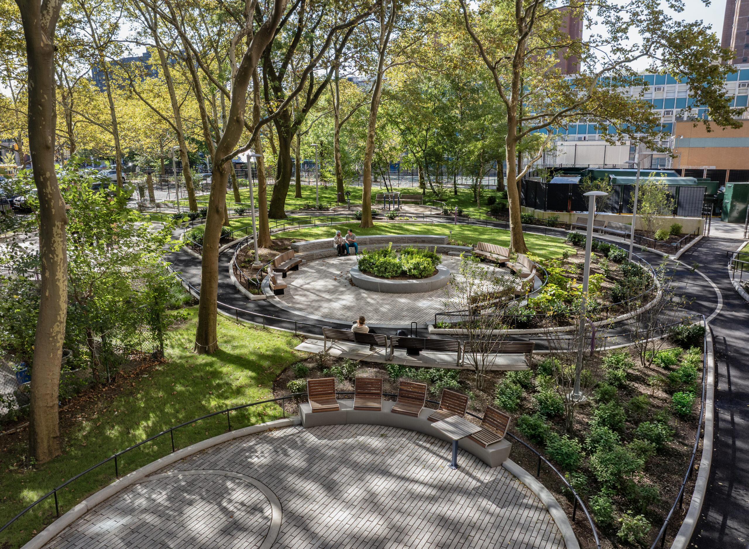 Bethune Gardens – Granite Amphitheater Seating Granite amphitheater seating surrounded by native planting beneath mature canopy trees at Bethune Gardens NYCHA PACT landscape renovation in Manhattan